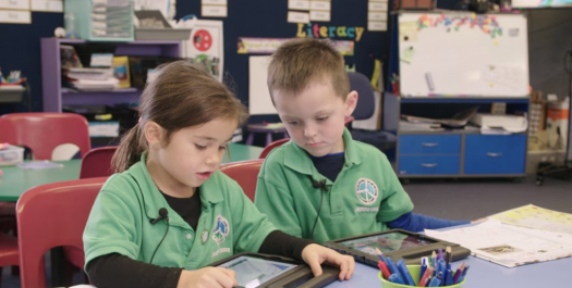 Two young students wirking together with iPads